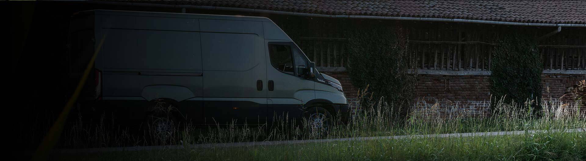 Samochód dostawczy Iveco Daily zaparkowany przy budynku gospodarczym – nowoczesny silnik Iveco zapewniający wysoką moc, oszczędność paliwa i niezawodność w codziennej eksploatacji