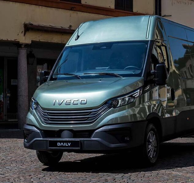 Samochód dostawczy Iveco Daily zaparkowany przed budynkiem serwisu – autoryzowany serwis Iveco oferujący kompleksową pomoc techniczną i naprawy w sieci Uni-Truck