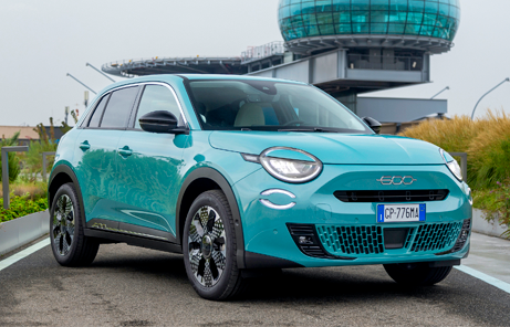 Fiat 600 Hybrid w kolorze turkusowym przed budynkiem – nowoczesny miejski crossover