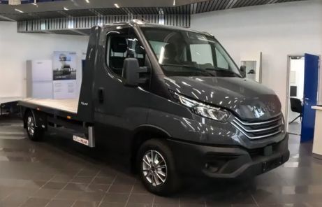 Iveco Daily z zabudową lawety zaparkowane w salonie – promocyjna oferta samochodów do transportu pojazdów w Uni-Truck.